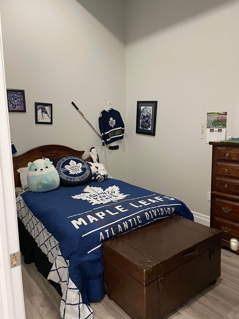 A bedroom with a bed covered in a blue blanket that says "Maple Leafs" on it.