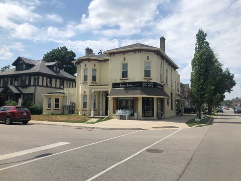 A street view with a building on the right and a car on the left.