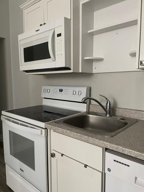 A white microwave oven is mounted above a white stove in a kitchen.