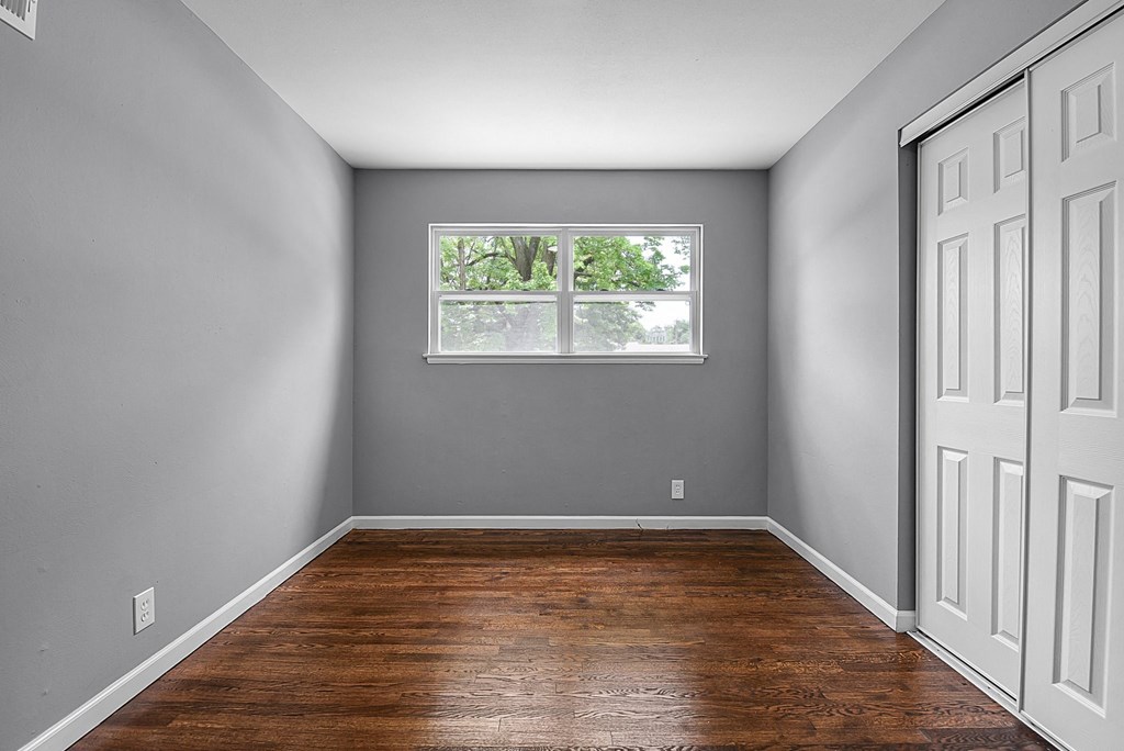 an empty room with wood floors and a window