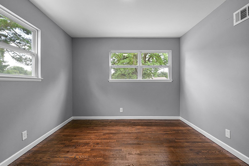 an empty room with wood floors and a window