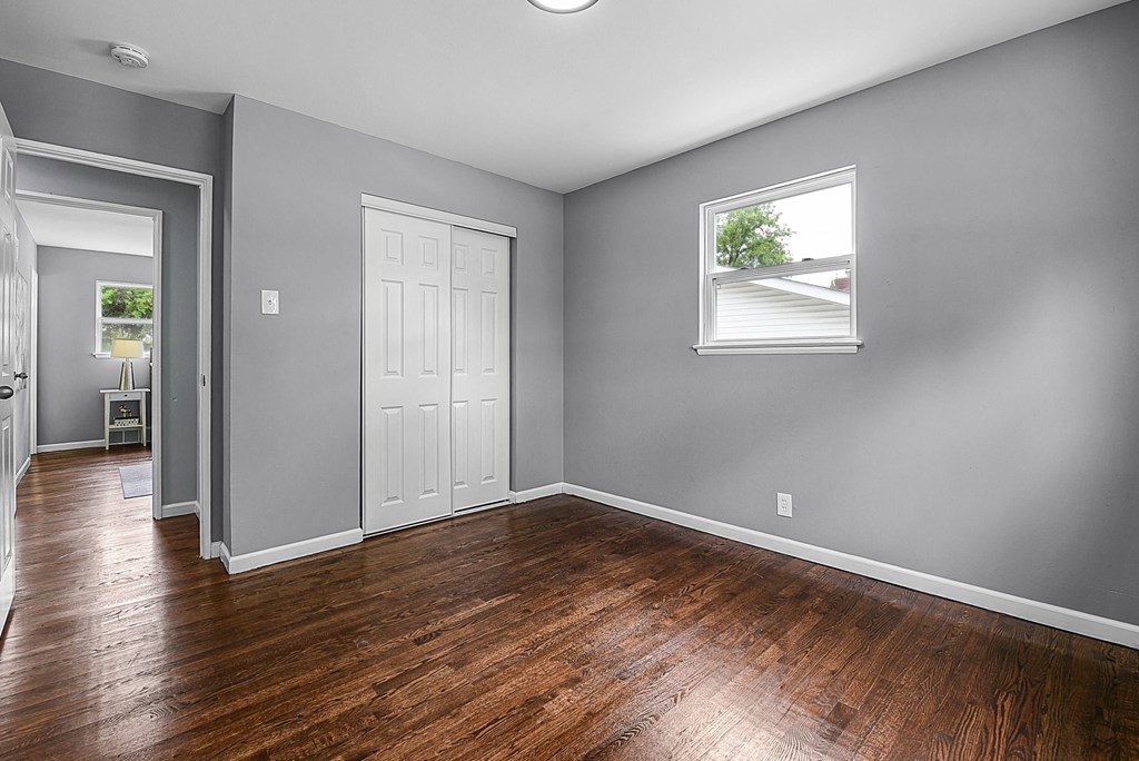 an empty living room with wood floors and a window