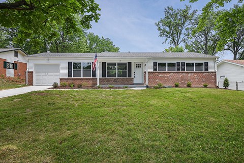 a white and brick house with a lawn in front