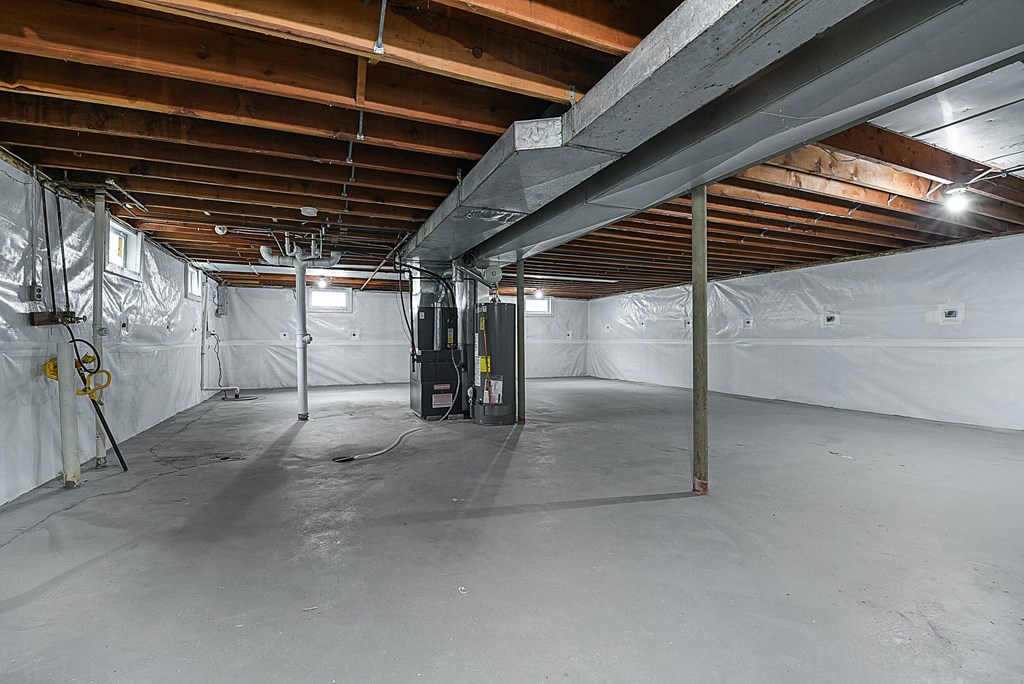 a large unfinished basement with white walls and exposed wood ceilings