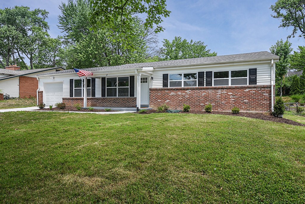 a white and brick house with an flag in the yard