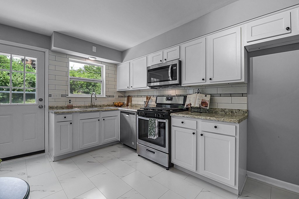a kitchen with white cabinets and a stove and a microwave