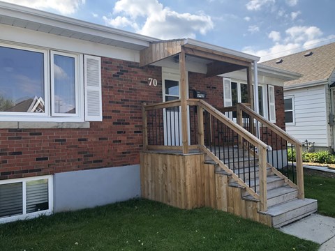 A house numbered 70 with a wooden deck and stairs.