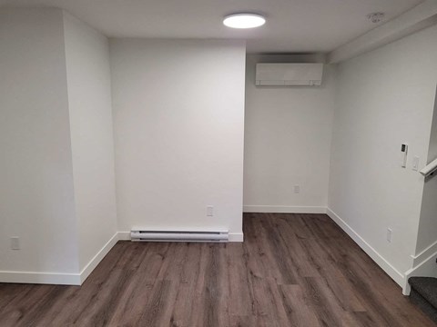 A room with wooden flooring and white walls.