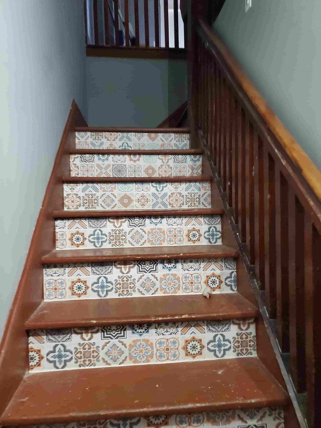 a set of tiled stairs with a wooden railing and a patterned stair runner