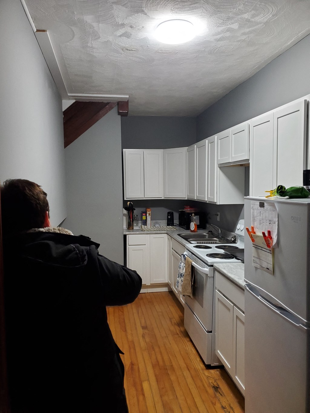 a person looking at a kitchen with white cabinets and a refrigerator