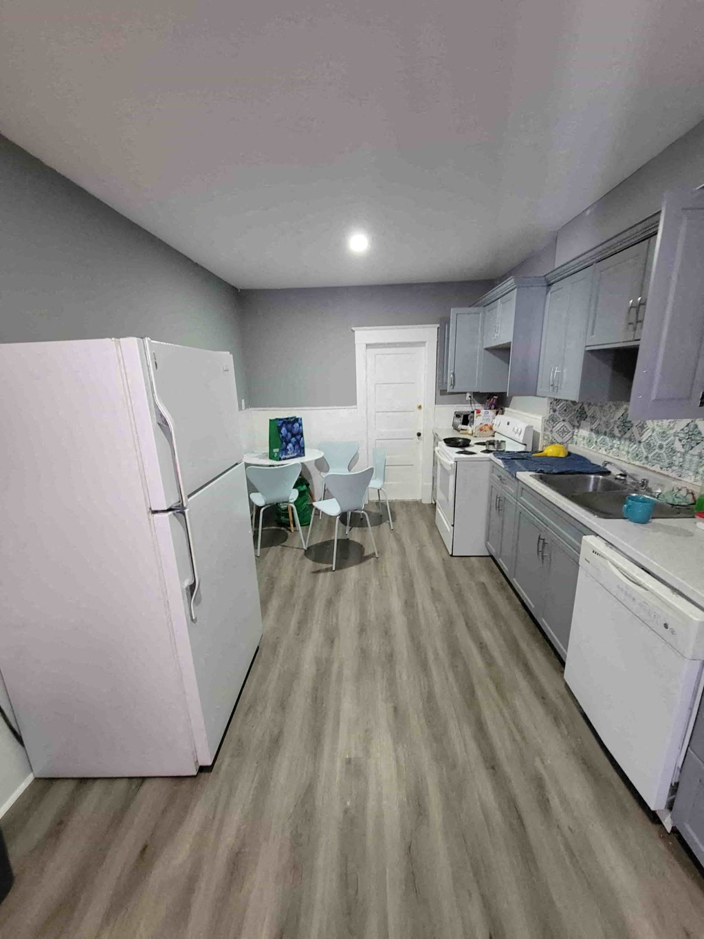 a kitchen with white appliances and a table and chairs