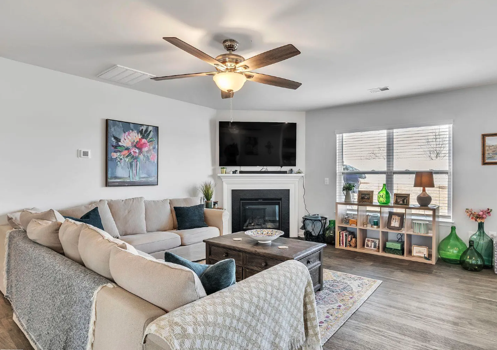 a living room with a fireplace and a ceiling fan