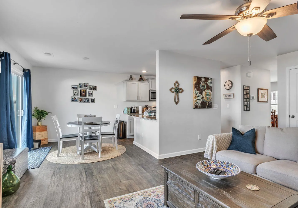 a living room with a table and a ceiling fan