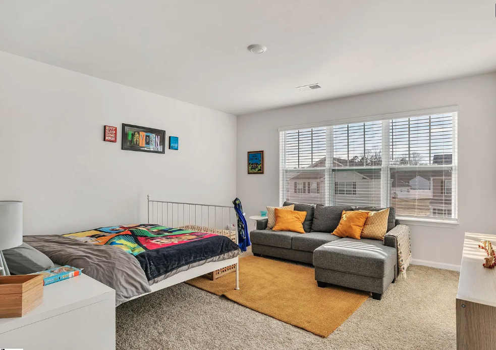 a bedroom with a bed and a couch in front of a window