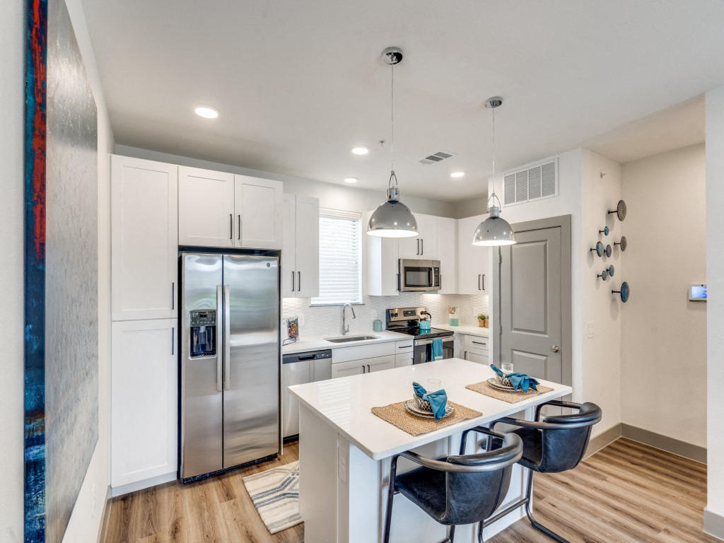 a white kitchen with stainless steel appliances and a white table