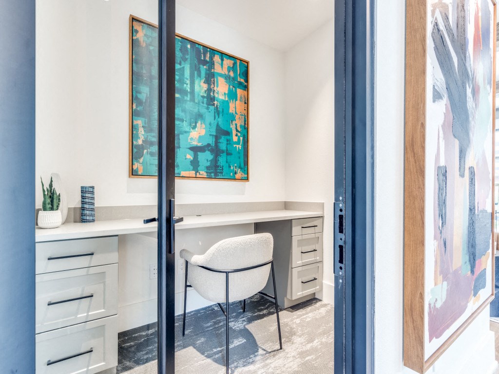 a room with a desk and a chair and a painting on the wall