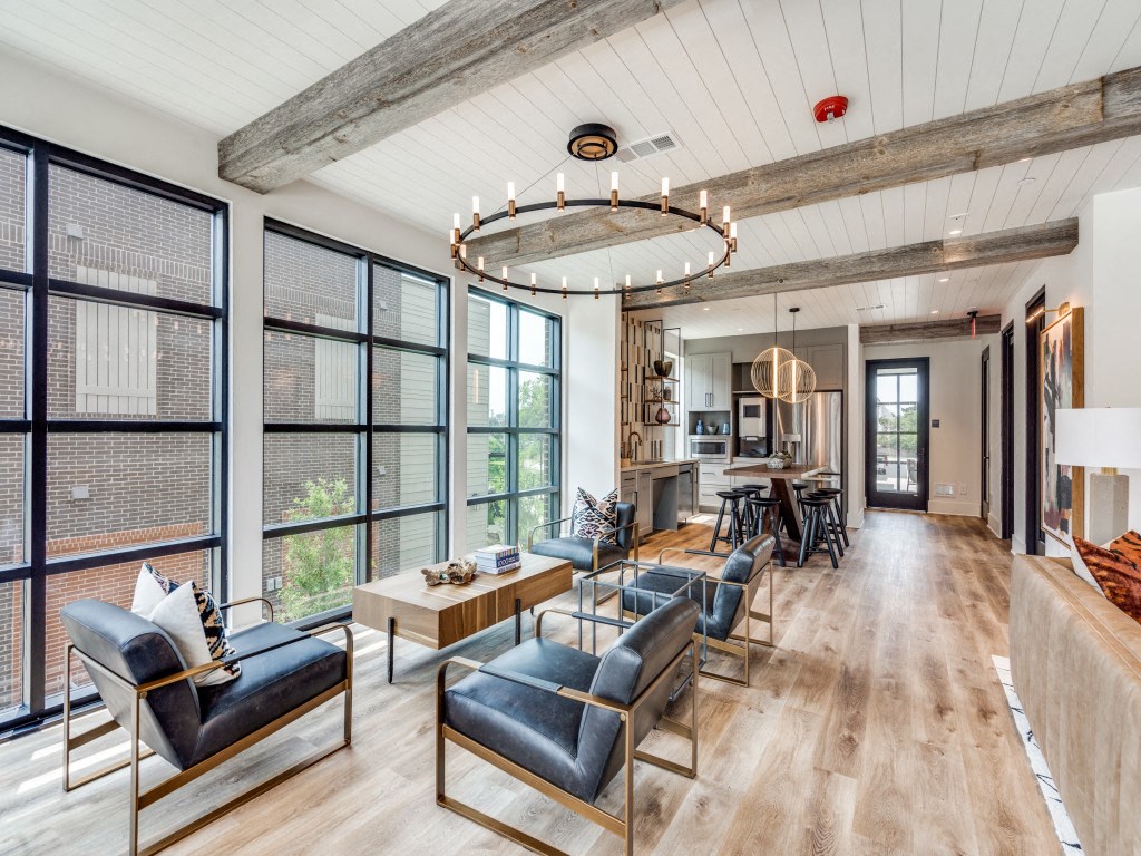 a living room with leather chairs and a kitchen with large windows