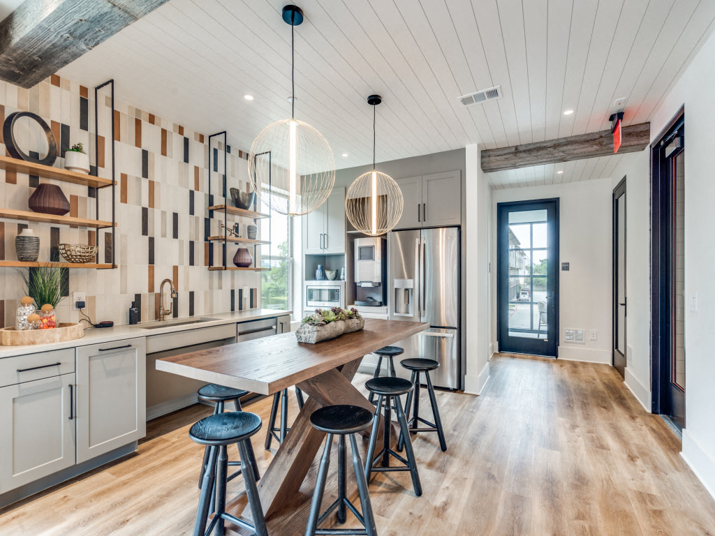 a kitchen with a long wooden table and bar stools