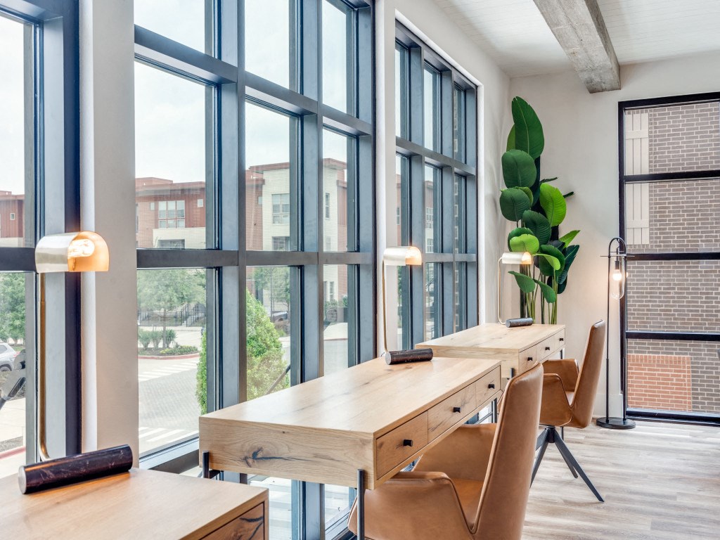 a conference room with large windows and a wooden desk and chairs