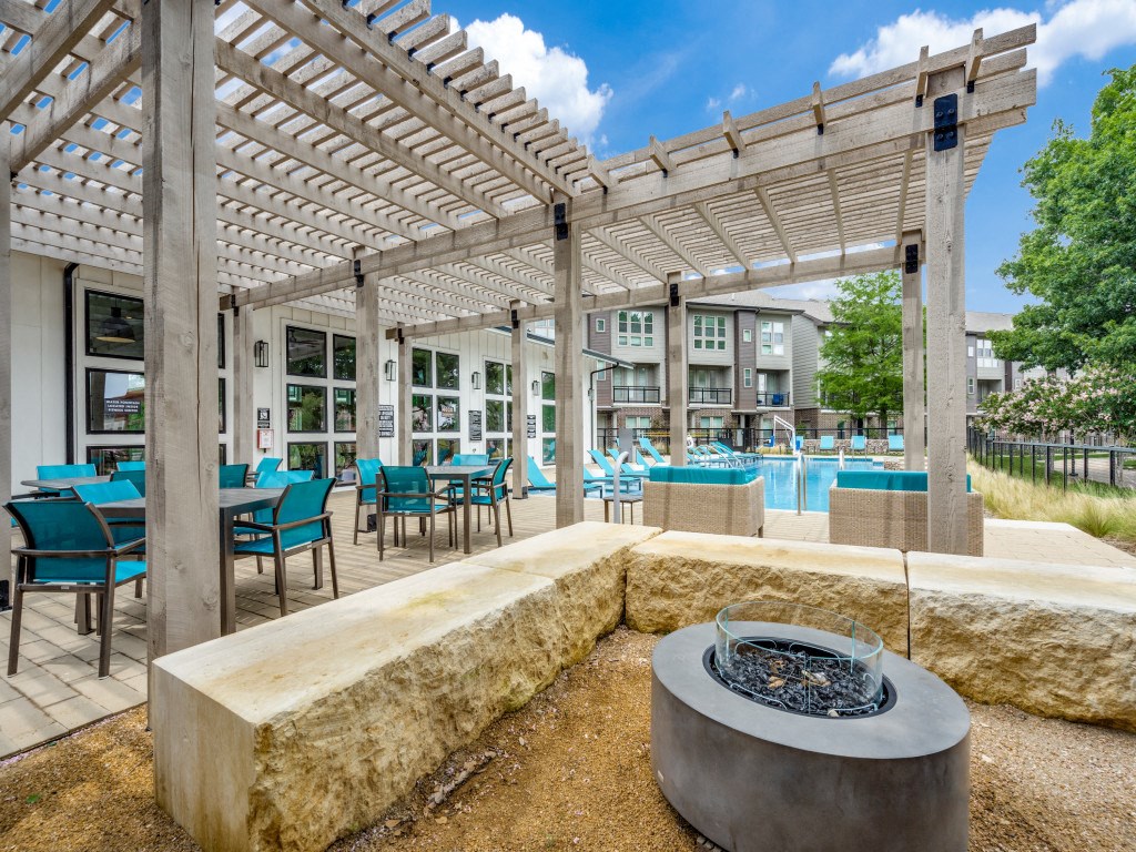 a patio with tables and chairs and a fire pit