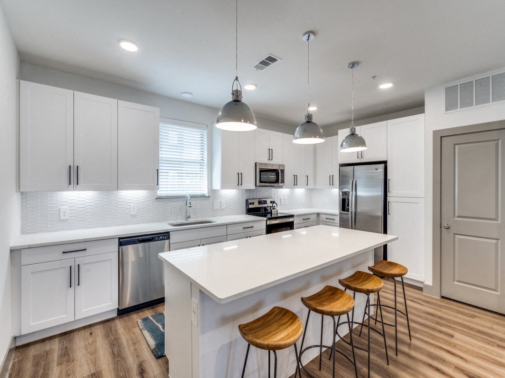 a white kitchen with a large island and bar stools