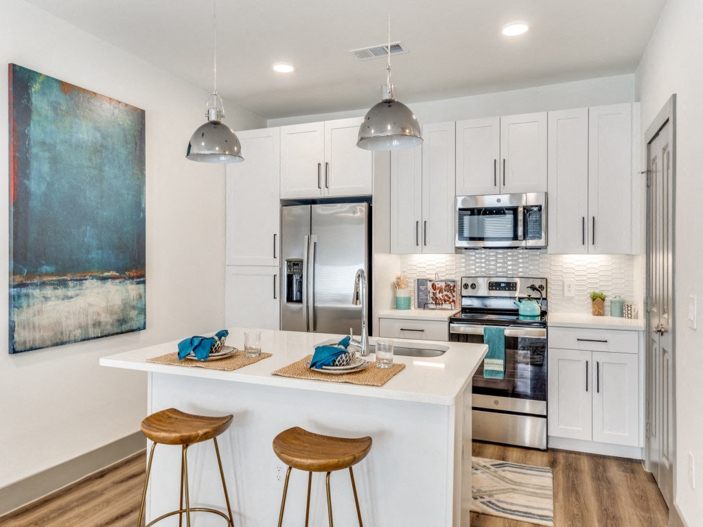 a kitchen with white cabinets and a white island with two stools