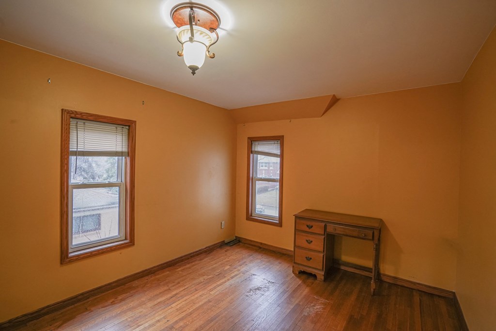 an empty room with a desk and two windows