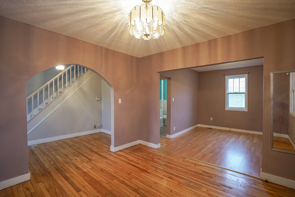 an empty living room with a hard wood floor and a staircase