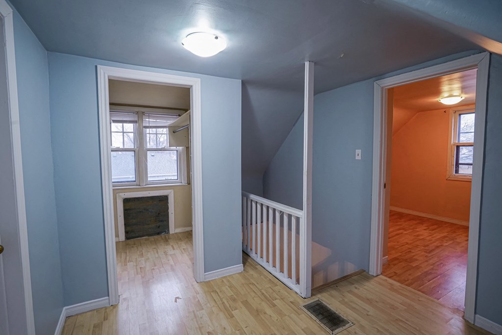 a room with a staircase and a window and a blue wall and a wood floor