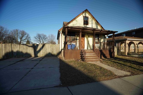 the front of a house with a sidewalk and a fence