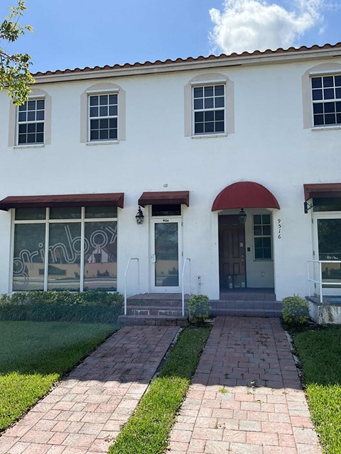 A white building with a red awning and a glass door.