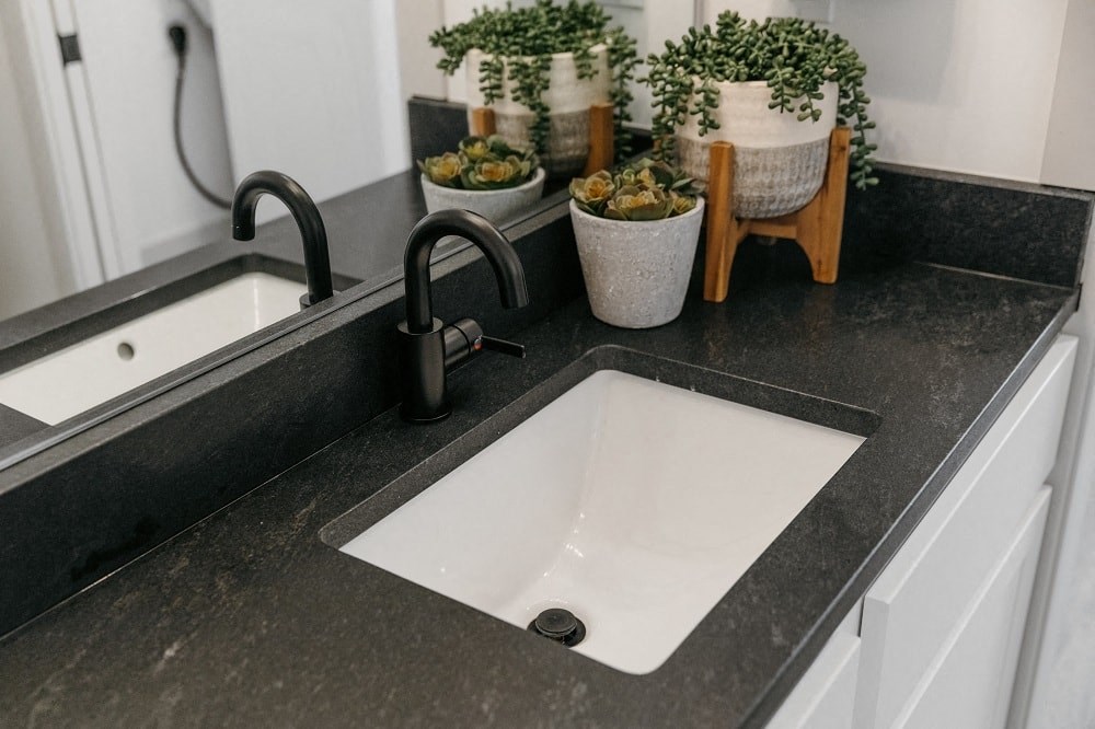 a black counter top with a white sink and a black faucet