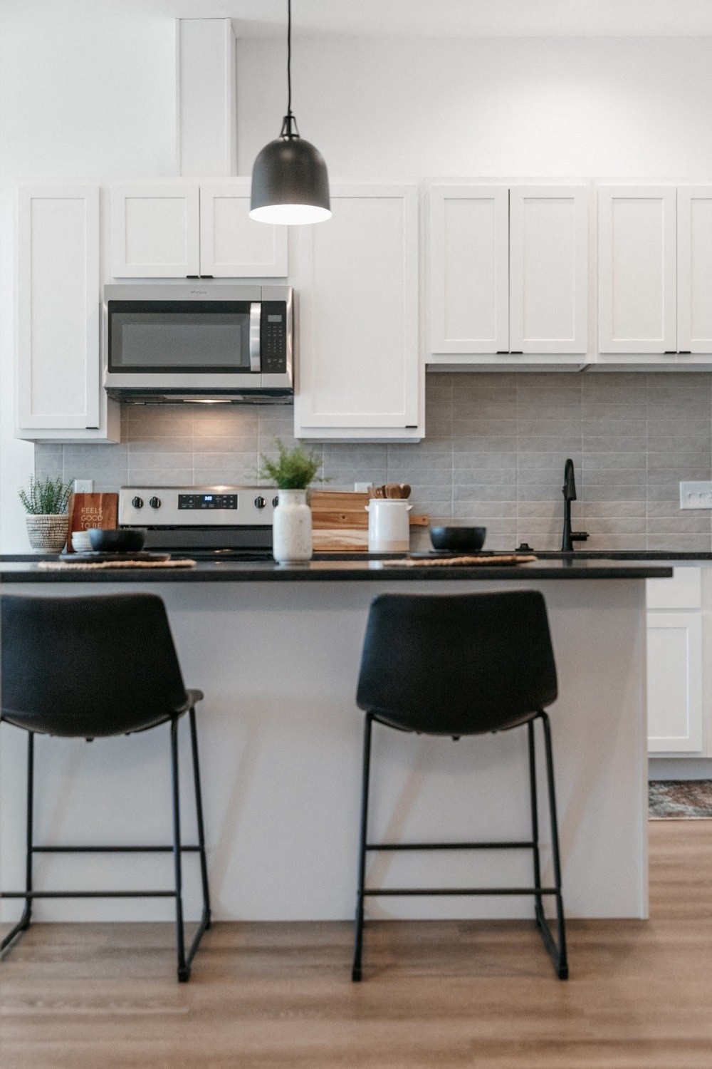 a kitchen with white cabinets and a counter top with two black chairs
