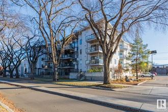 an apartment building on the corner of a street with trees