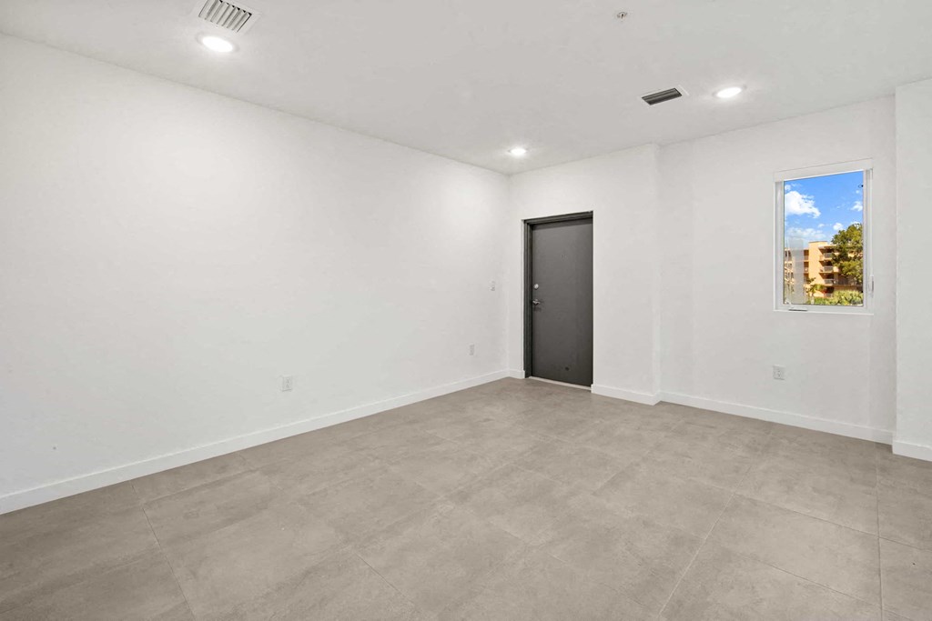 an empty living room with white walls and a black door