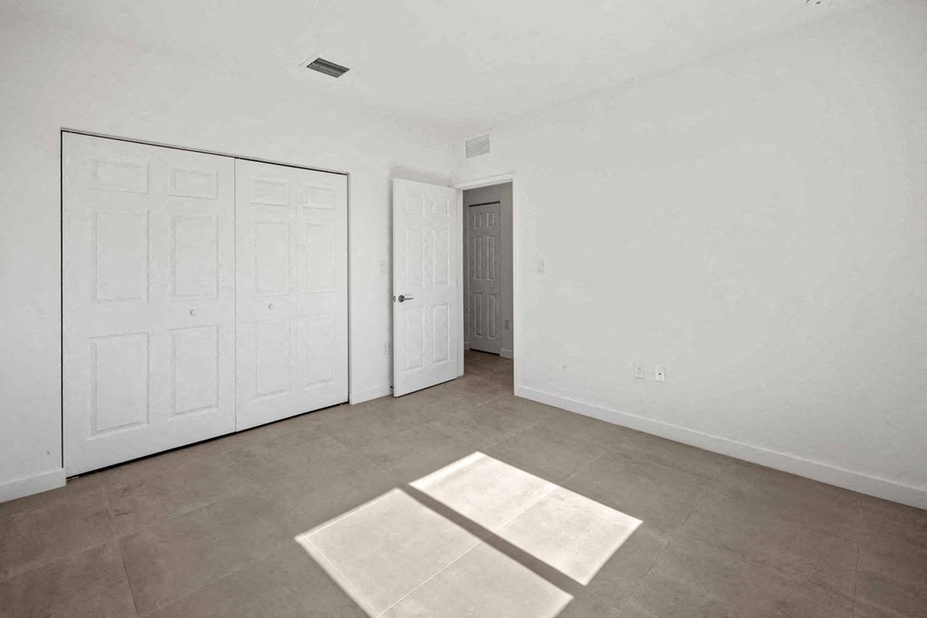 an empty living room with white walls and a door to a closet