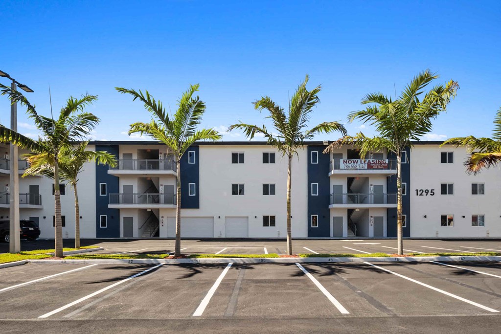 a parking lot with palm trees in front of an apartment building