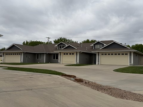 A grey house with a grey roof and grey garage doors.