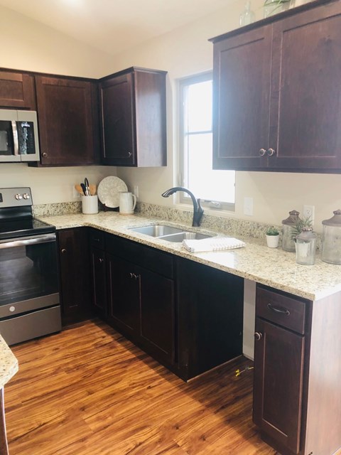 A kitchen with dark wood cabinets and a granite countertop.