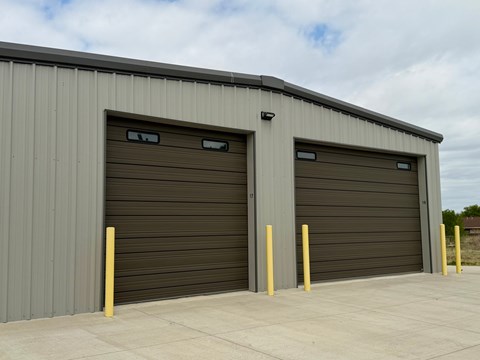 Two garage doors are closed and have yellow posts in front of them.