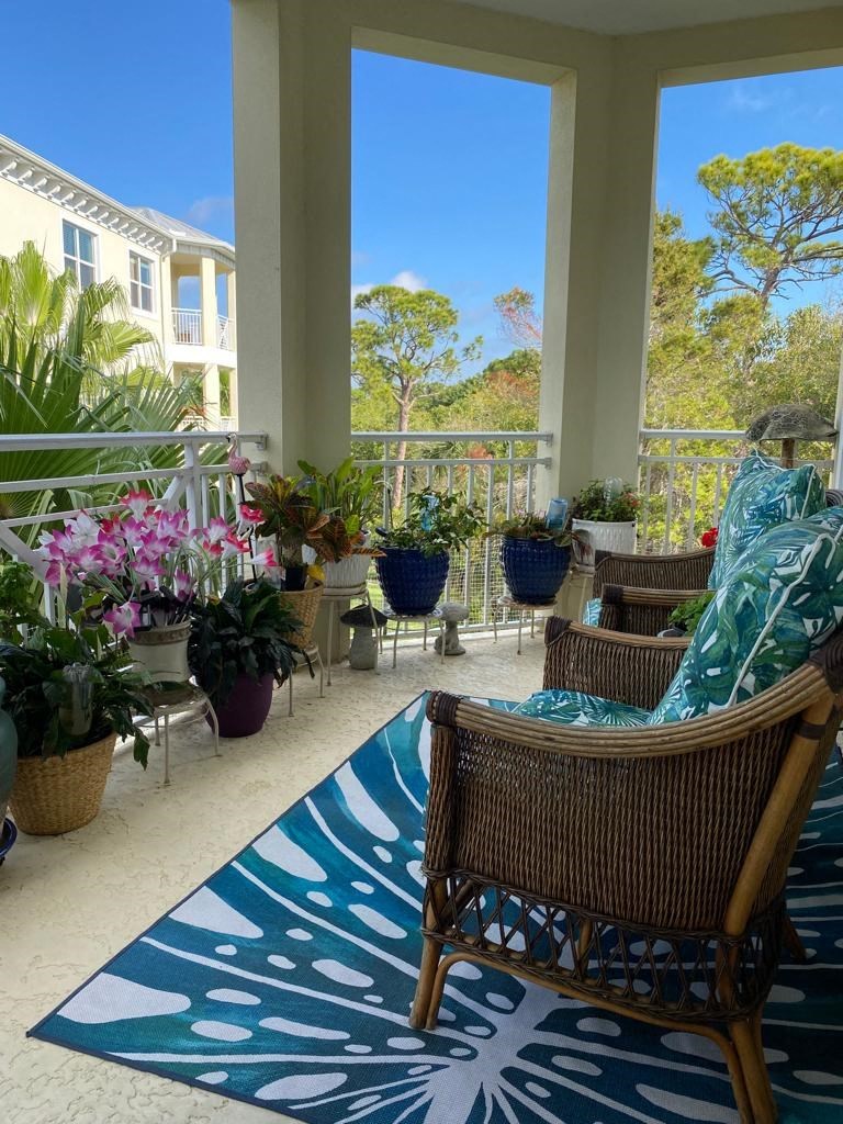 a porch with chairs and potted plants and a rug