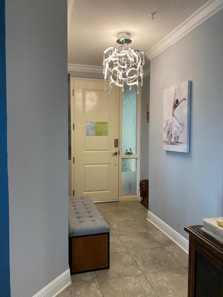 a hallway with a white door and a chandelier