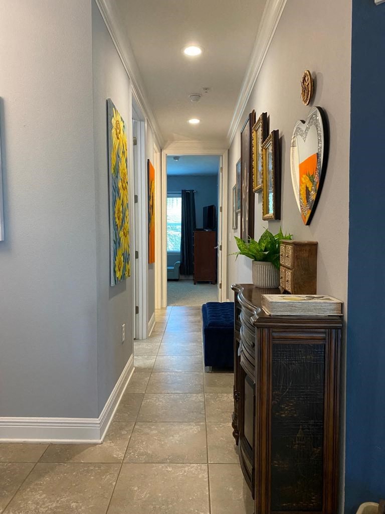 a long hallway with a dresser and paintings on the wall