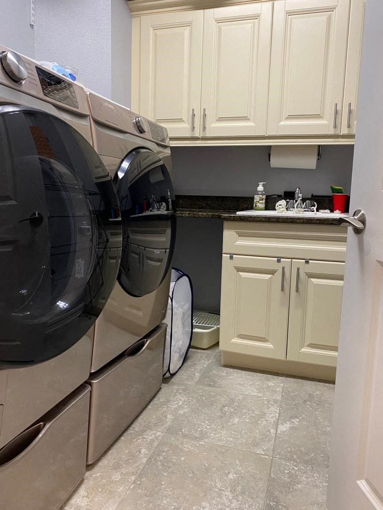 a washer and dryer in a laundry room with white cabinets