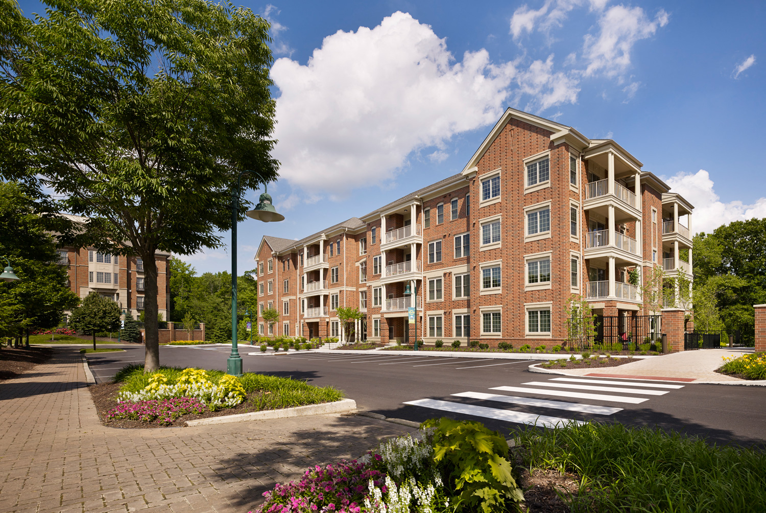 Exterior View of Claremont on the Square 4-story apartment buildings in Exton, PA with nearby resident parking and beautiful trees and flowers.