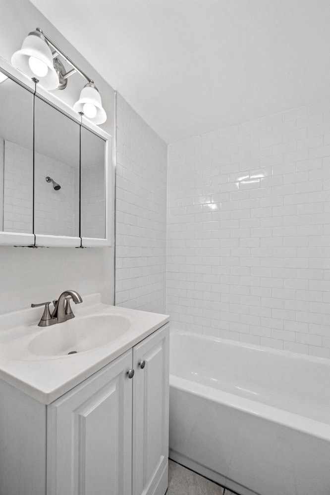 a white bathroom with a sink and a tub