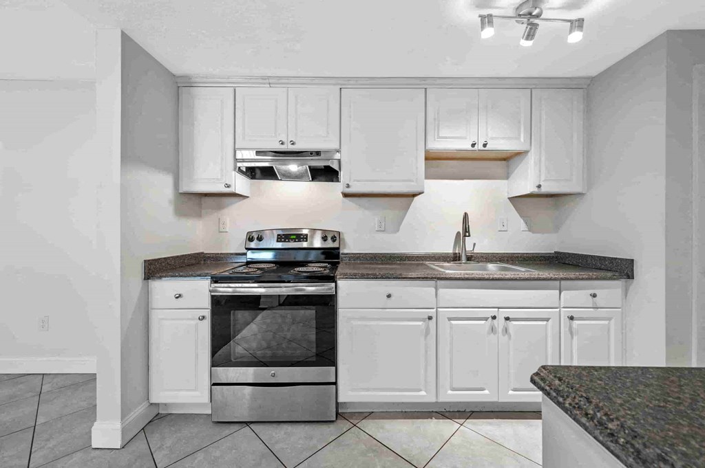 a kitchen with white cabinets and a stove and a sink