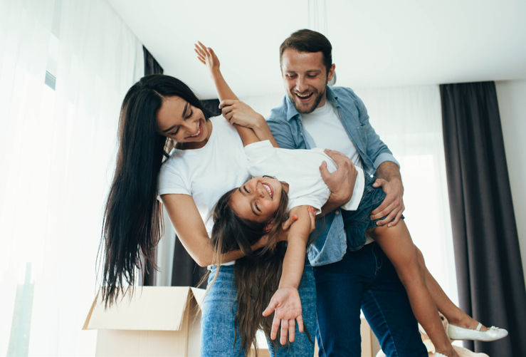 two women and a man playing with a child in a living room