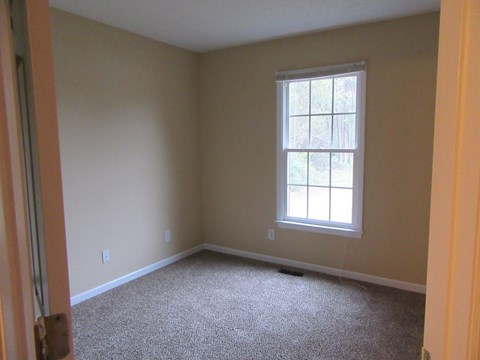 A room with a window and carpeted floor.