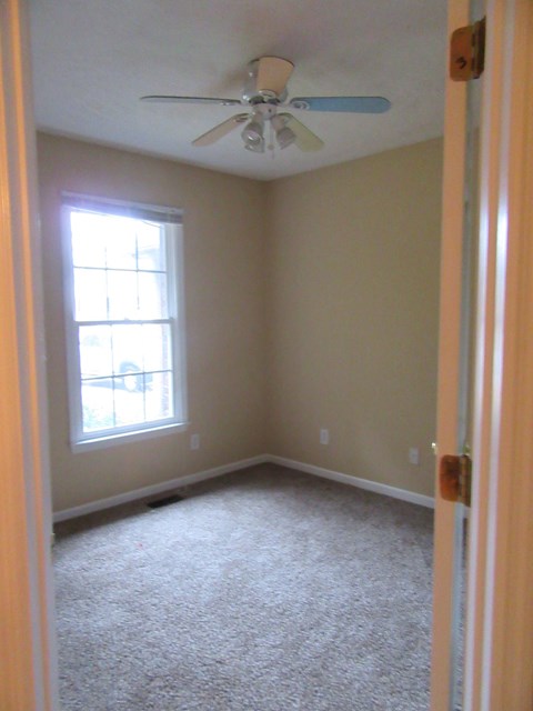 A room with a ceiling fan and a window.